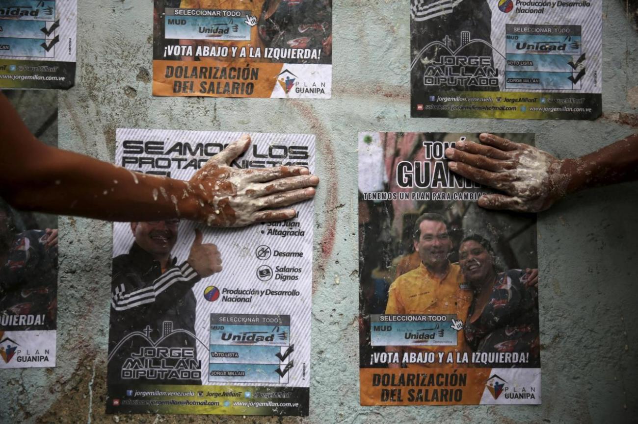 Reuters.opposition-supporters-use-their-hands-to-glue-posters-of-candidates-from-the-venezuelan-coalition-of-opposition-parties-in-caracas